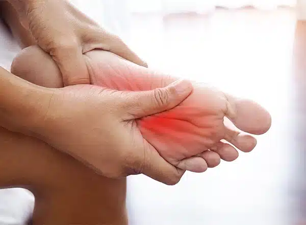 Close-up of a person using their thumbs to perform a deep tissue self-massage on a red, inflamed area of the ball of the