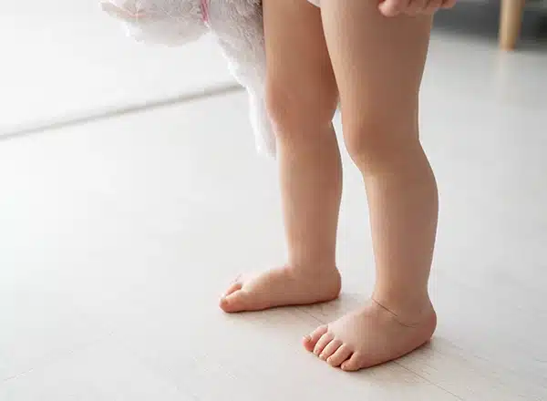 close-up of a physical therapist's hands performing a foot mobilization technique on a patient's foot, which is resting on a blue foam block during a clinical rehabilitation session.