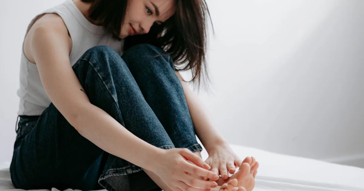 Patient experiencing first-step morning foot pain from plantar fasciitis on bedroom floor Howell MI