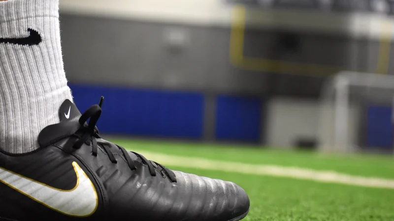 Soccer cleat planted on artificial turf, the surface turf toe is named for - Balance Foot & Ankle, Howell MI