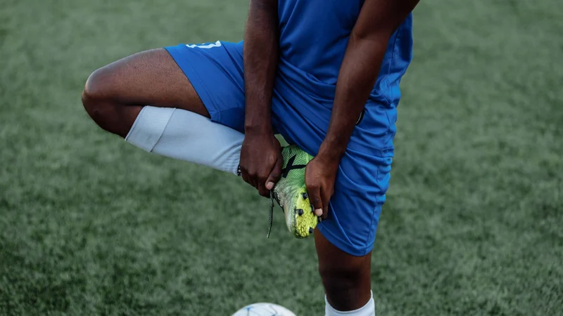 Athlete stretching on a grass field during turf toe return-to-play - Balance Foot & Ankle, Howell MI