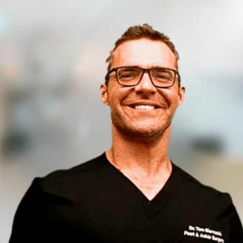 Dr. Tom Biernacki, foot and ankle surgeon, smiling, wearing black scrubs